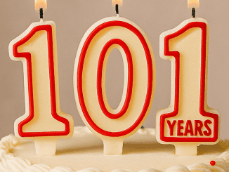 A colorful birthday cake with lit candles displaying “101,” symbolizing the celebration of the age of the longest living celebrities.